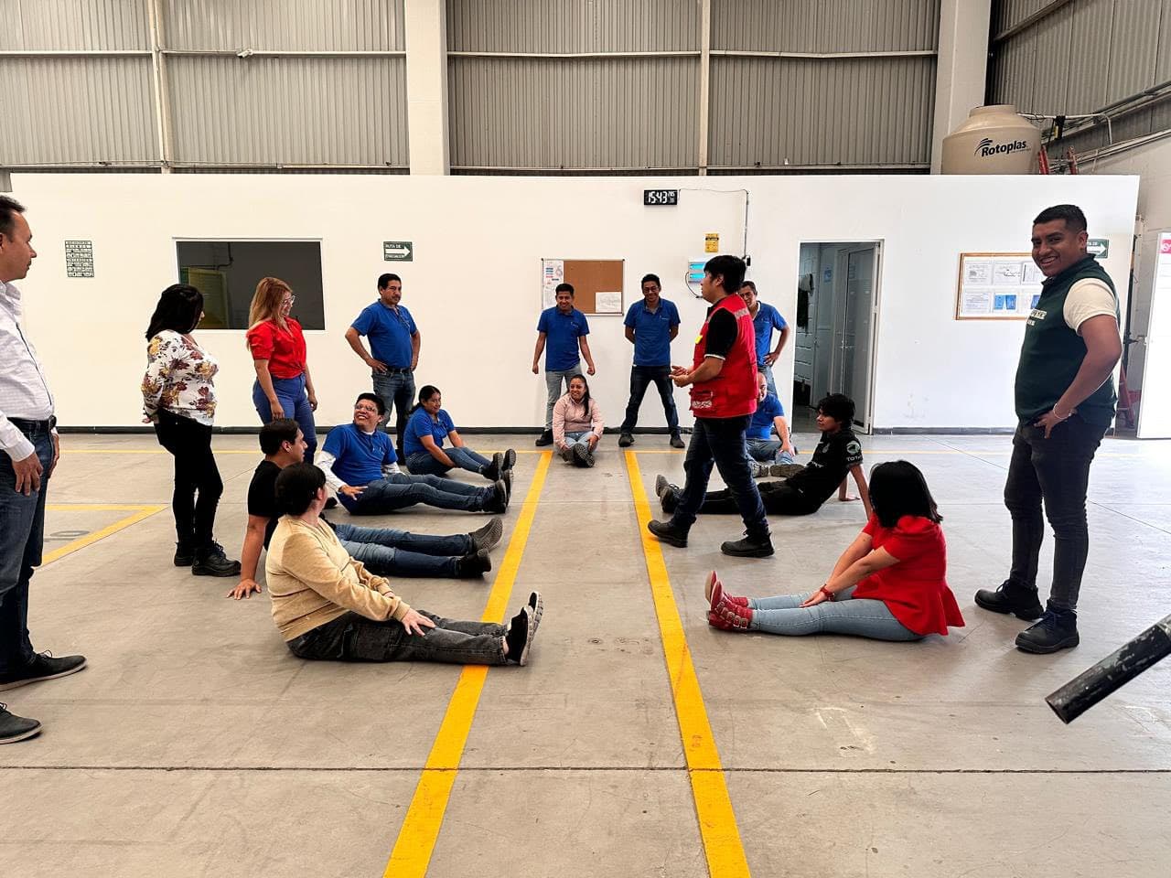 Brigadistas practican posiciones de seguridad en el piso de una nave industrial