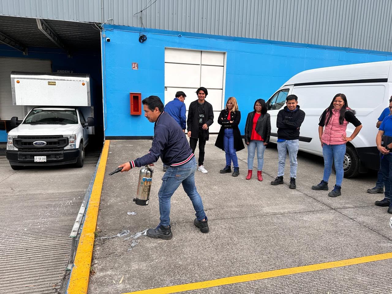 Participante acciona un extintor en el patio de maniobras durante un curso de combate contra incendios
